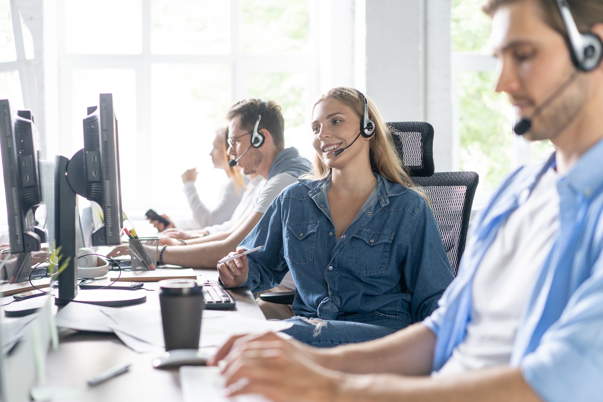 Young handsome male customer support phone operator with headset working in call center